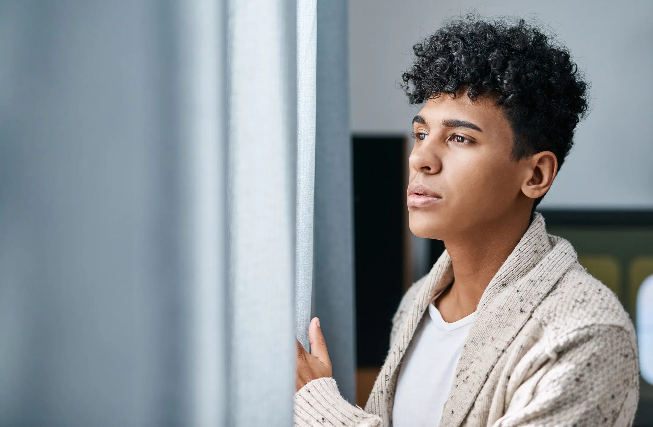 A lonely man longingly looks out his bedroom window